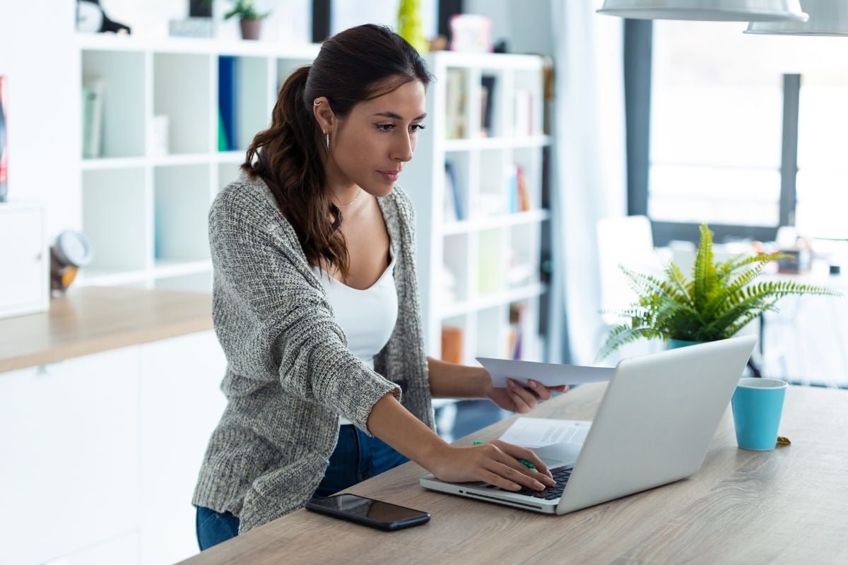 Woman using laptop at home to compare at-home STD testing options.